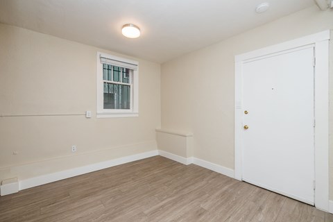 A room with a white door and a window with bars.