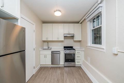 A kitchen with a refrigerator, oven, and sink.