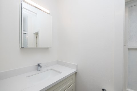 A white sink in a bathroom with a mirror above it.