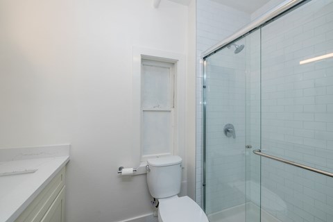 A white toilet sits next to a glass shower door in a bathroom.