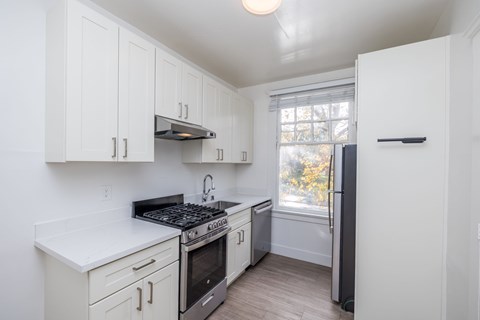 A kitchen with white cabinets and a black stove top.