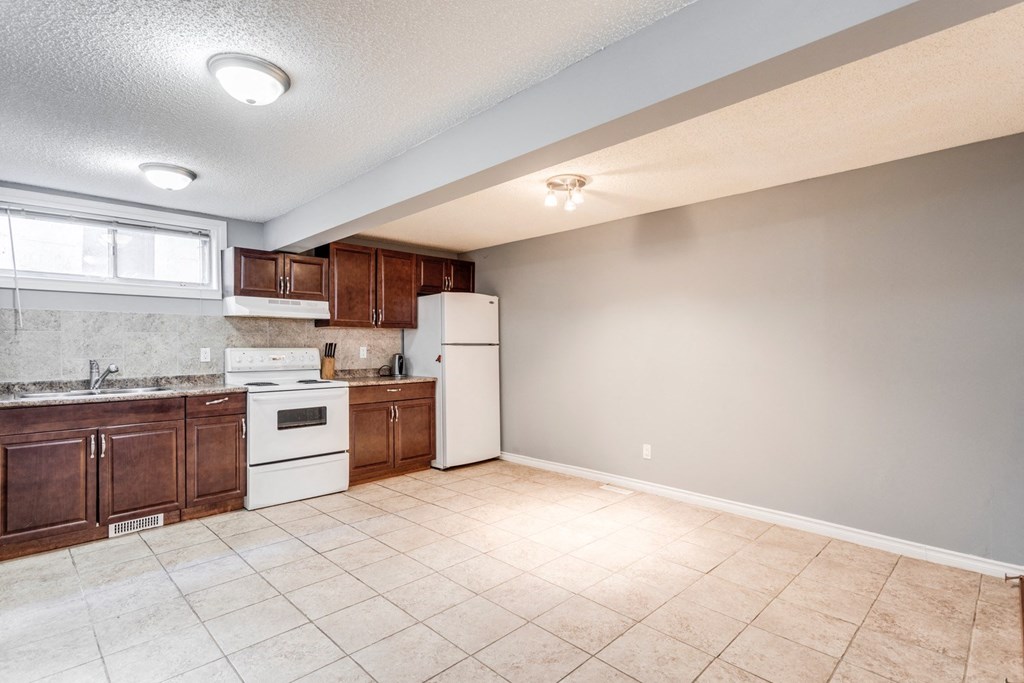 an empty kitchen with white appliances and wooden cabinets