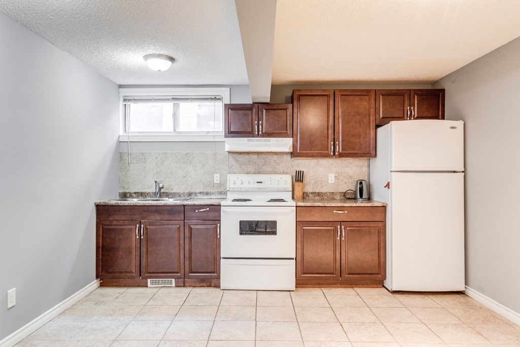 an empty kitchen with white appliances and wooden cabinets