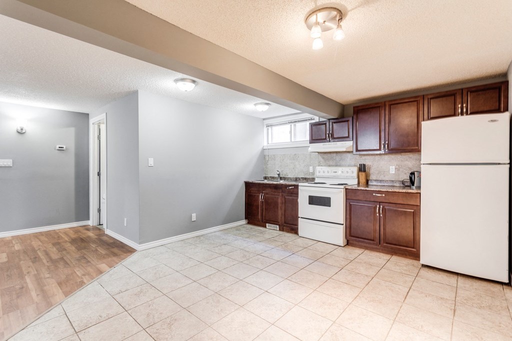 an empty kitchen with white appliances and wooden cabinets