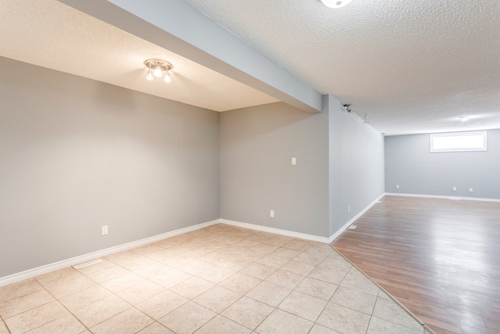 an empty living room with a tile floor and grey walls