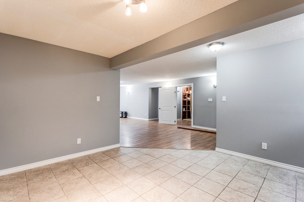 the living room and dining room in an empty house with tile flooring and gray