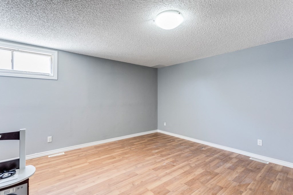 an empty living room with wood flooring and gray walls