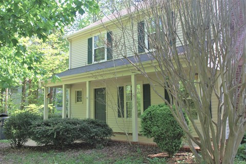 a yellow house with a large tree in front of it
