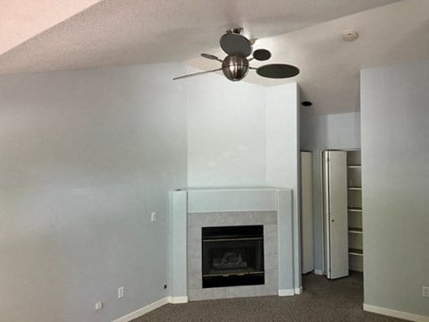 a living room with a fireplace and a ceiling fan