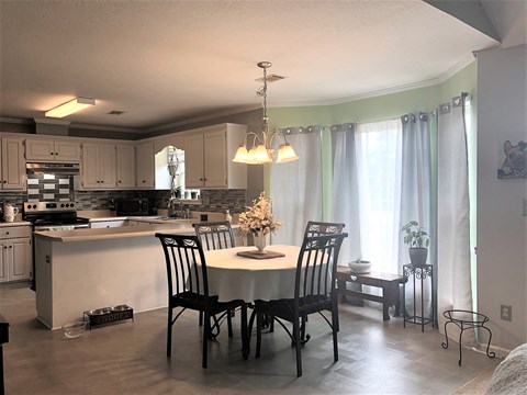 the kitchen and dining area of a home with a table and chairs