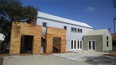 A white building with a grey addition and a brown door.