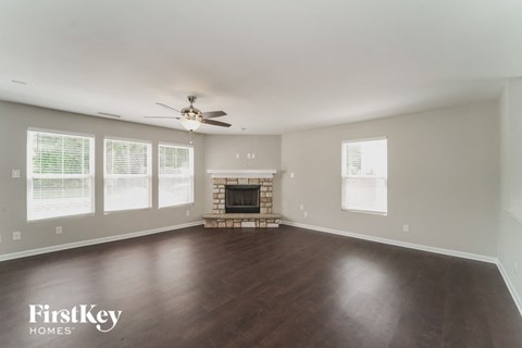 A spacious living room with a fireplace and a ceiling fan.
