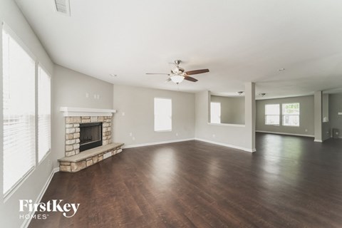 A spacious room with a fireplace and wooden floors.