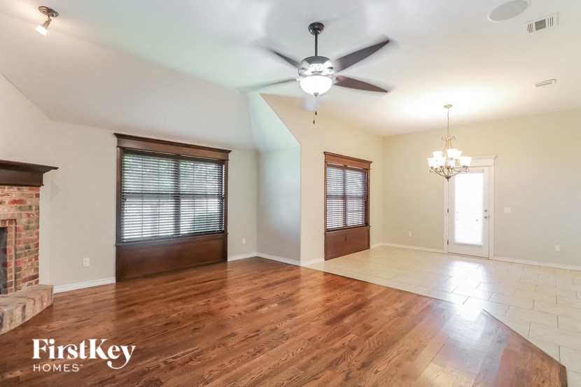 A spacious room with a fireplace and wood flooring.