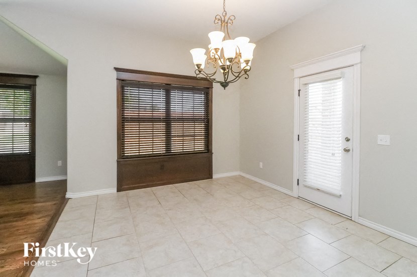 A room with a chandelier, a door, and a window with blinds.