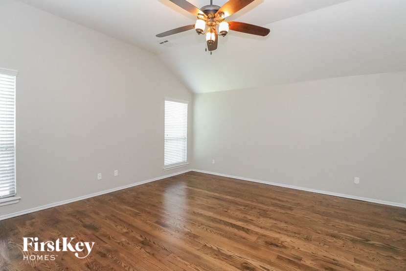 A room with a ceiling fan and wooden flooring.