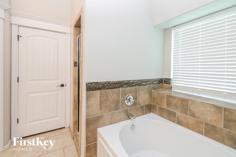A white bathroom with a tub and a door.