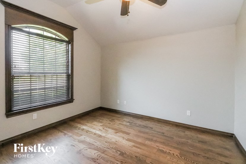 A room with wooden flooring and a window with blinds.