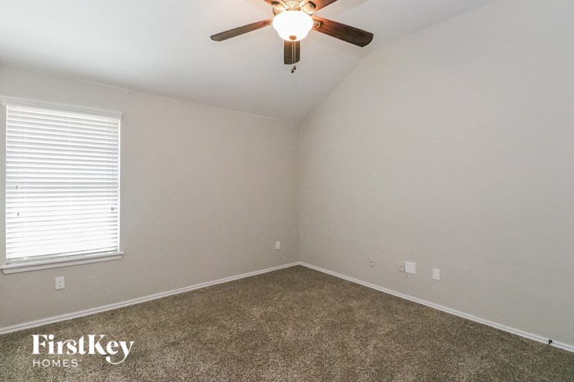 A room with a ceiling fan and a window with blinds.