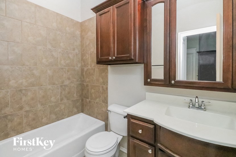 A bathroom with a toilet, sink and brown cabinets.