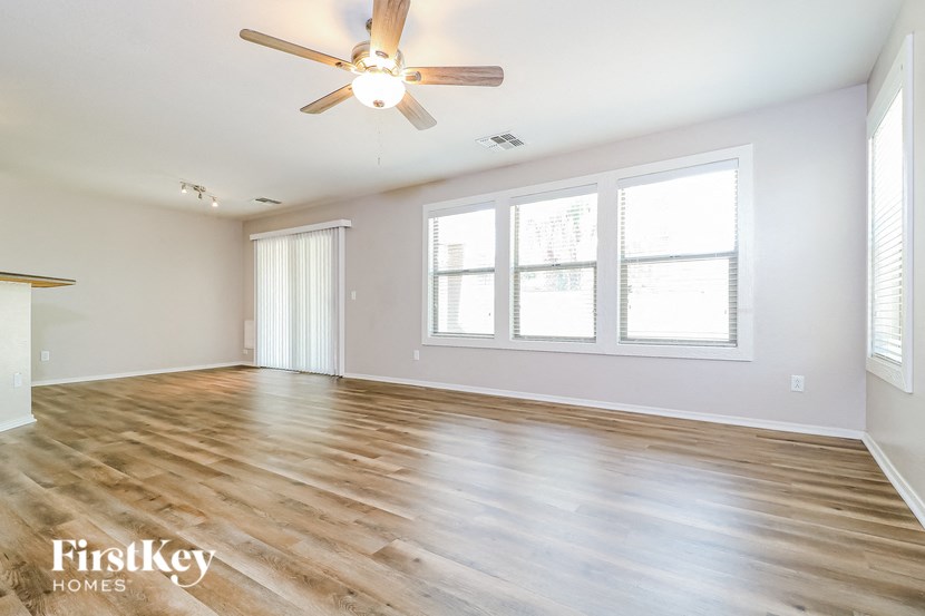 an empty living room with a ceiling fan and windows