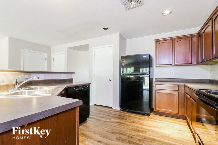a kitchen with black appliances and wood flooring and wooden cabinets