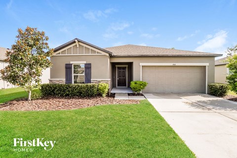 A house with a garage door and a tree in front of it.