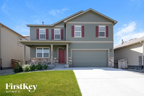 a beige house with red shutters and a driveway