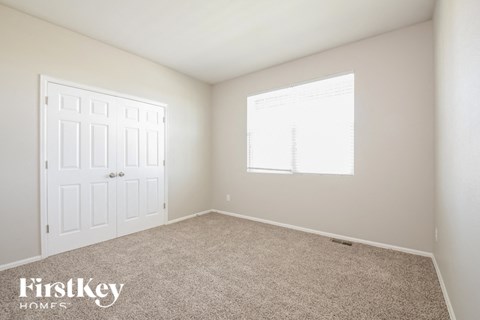 a bedroom with carpet and a white door and window