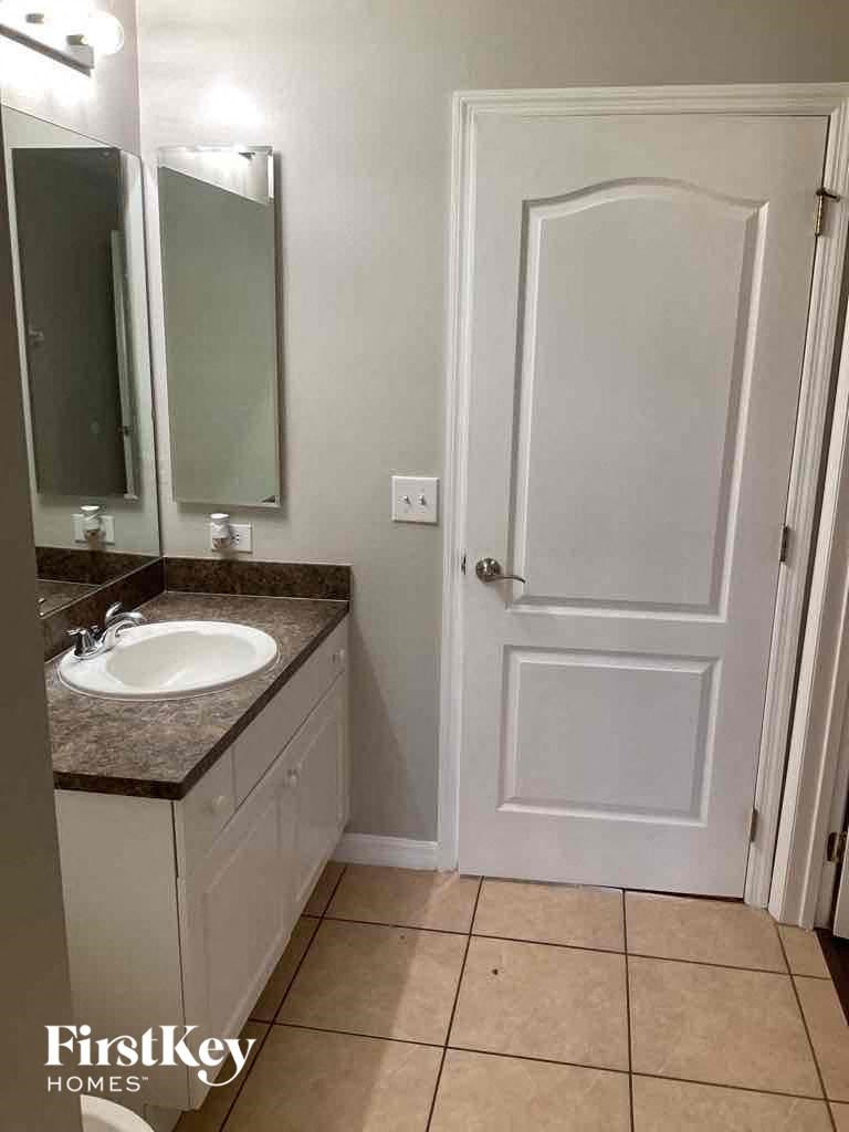 A bathroom with a sink, mirror, and door.