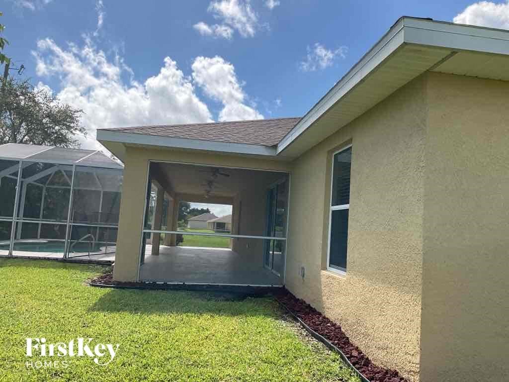 A house with a covered patio and a pool in the background.