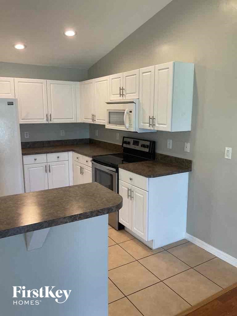 A kitchen with white cabinets and a black countertop.