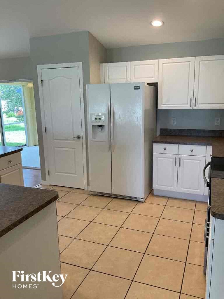 A kitchen with white cabinets and a white refrigerator.