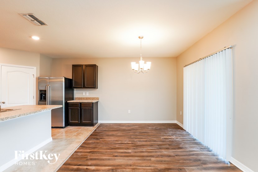 A spacious kitchen with wooden floors and a chandelier.