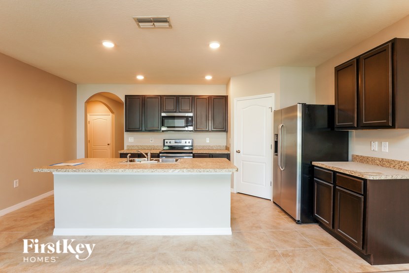 A kitchen with a white island and black appliances.