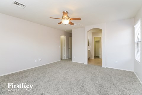 a spacious living room with carpet and a ceiling fan