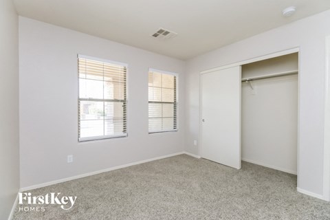 a bedroom with a closet and two windows and a door