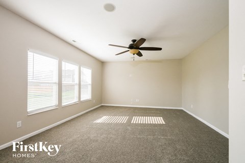 A spacious room with a ceiling fan and carpeted floor.