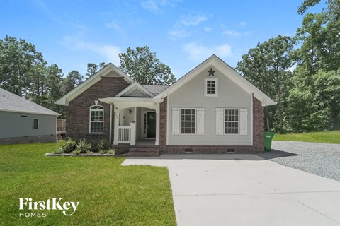 a white and brick house with a white sidewalk and grass