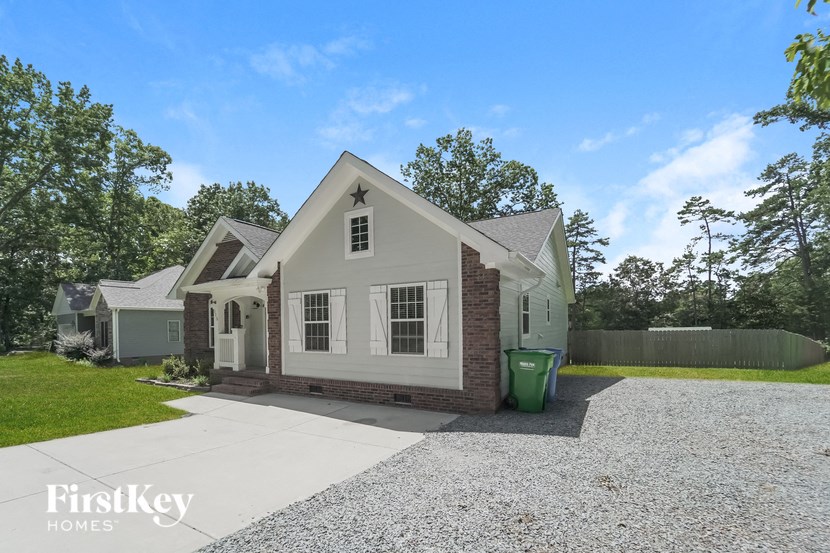 a small white house with a gravel driveway and a green yard