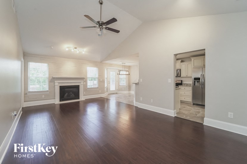 an empty living room with a fireplace and a ceiling fan