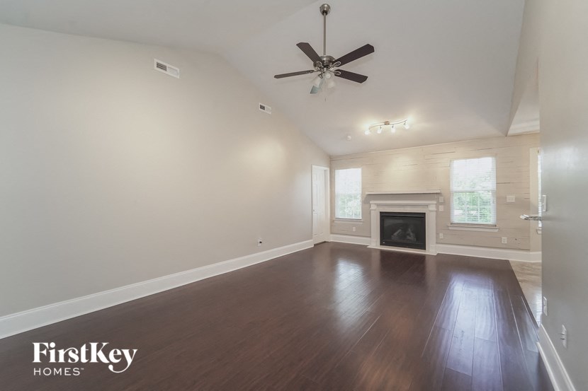 an empty living room with a ceiling fan and a fireplace