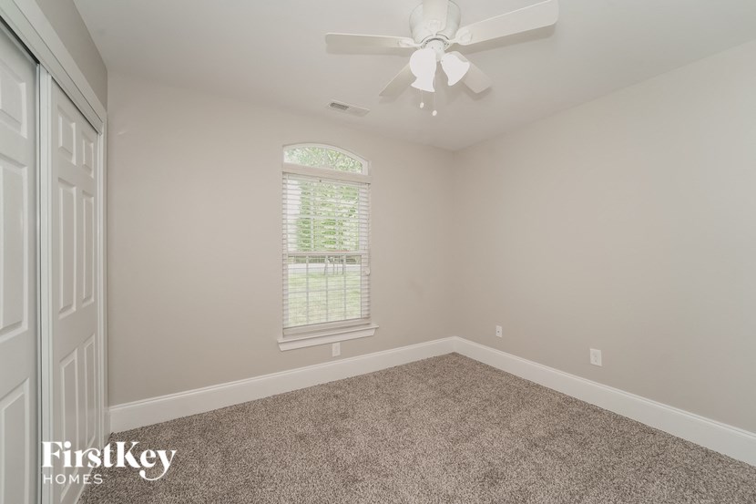 a empty bedroom with a ceiling fan and a window