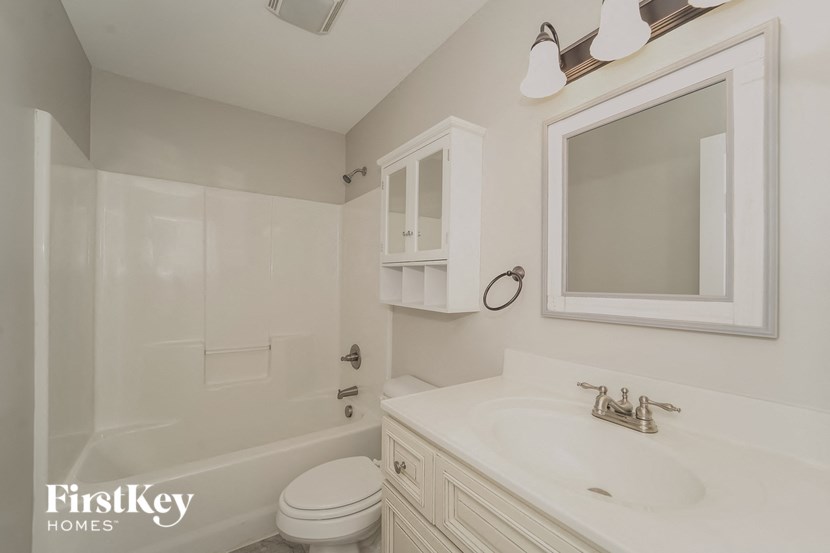 a white bathroom with a white sink and a toilet and a shower