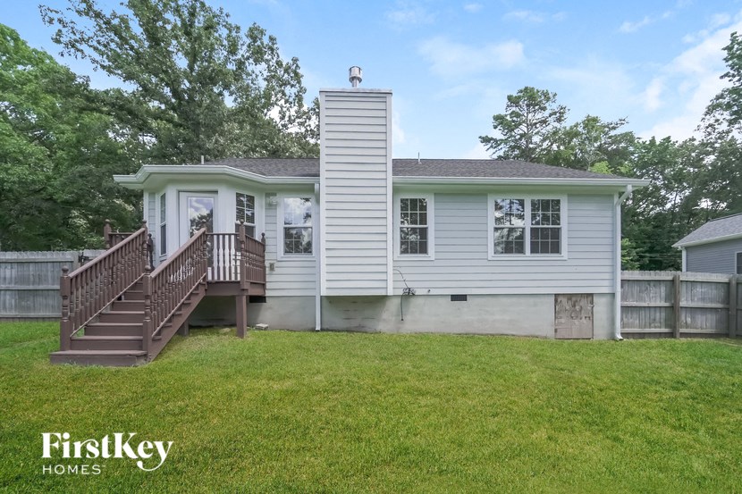 the exterior of a white house with a deck and a yard