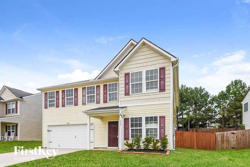 a yellow house with red shutters and a yard