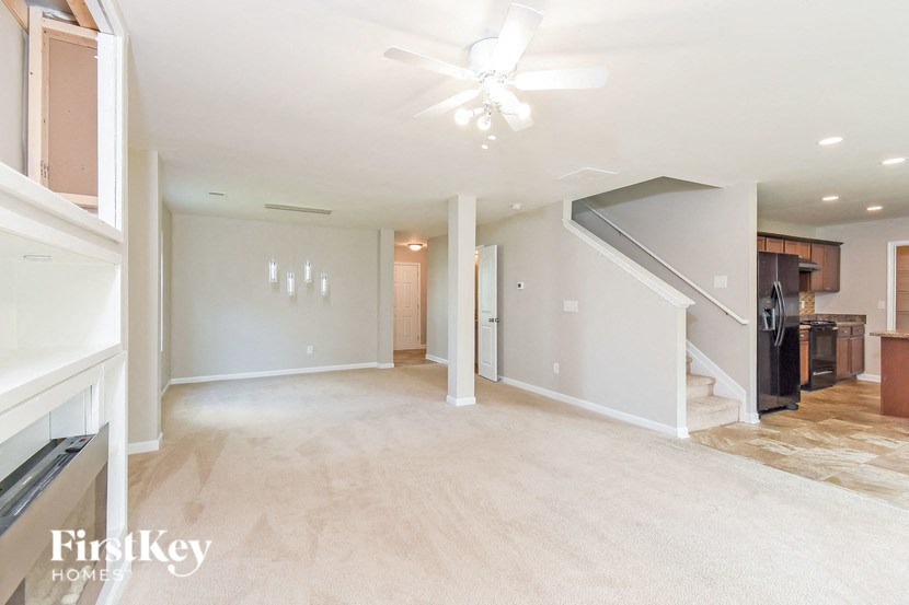 a empty living room with a ceiling fan and a kitchen
