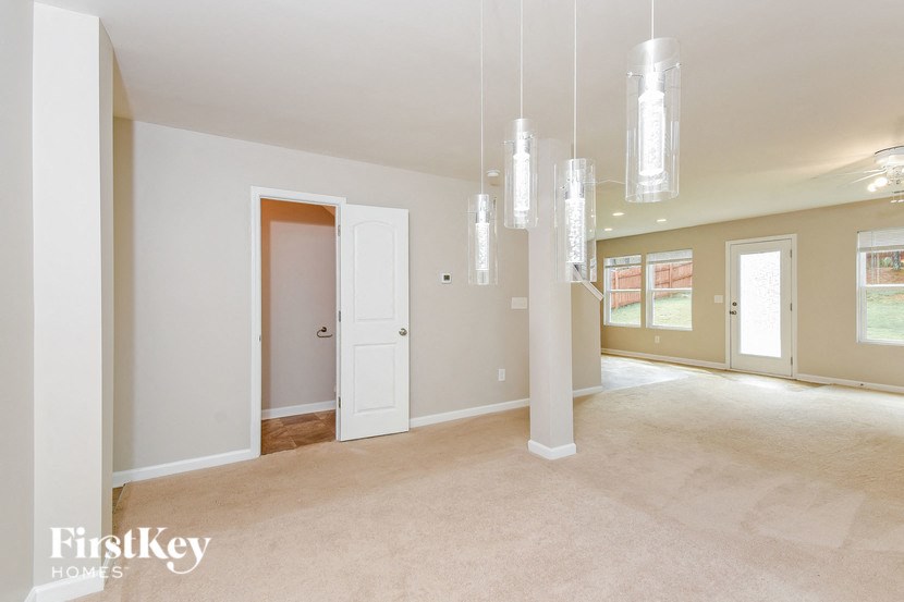 an empty living room and dining room with chandeliers