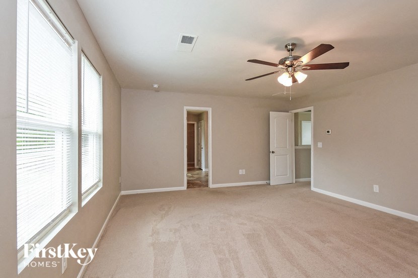 an empty living room with a ceiling fan and a large window