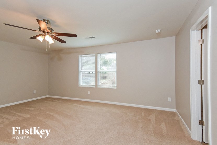 a empty living room with a ceiling fan and a window